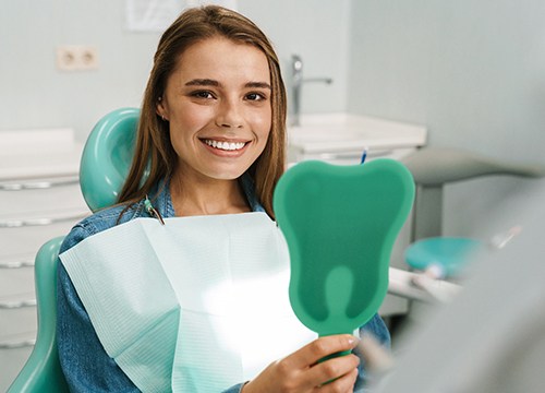 Woman looking at smile in handheld mirror