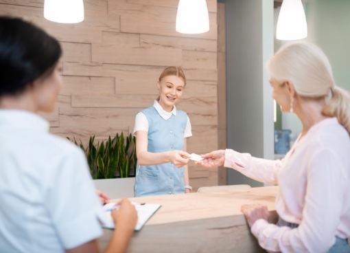 Woman handing payment card to dental receptionist
