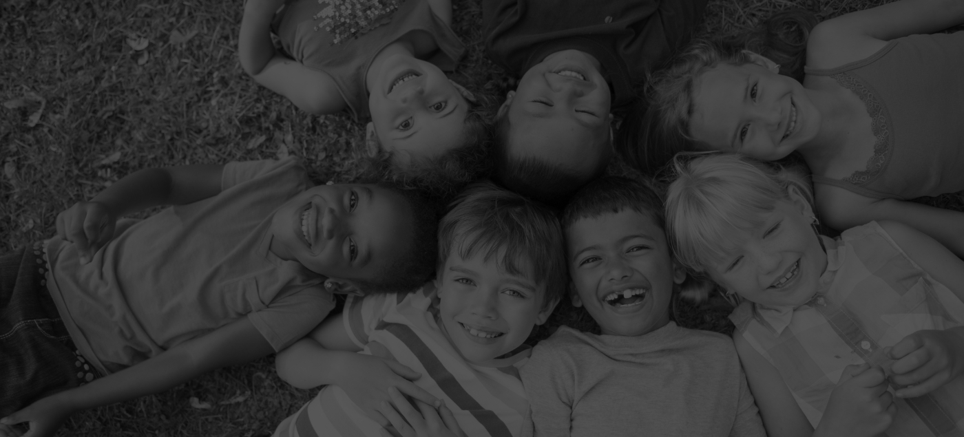 Group of smiling children sitting in circle with their heads touching in middle