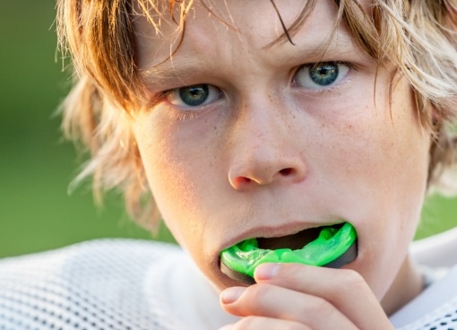 Young boy wearing green mouthguard over his teeth