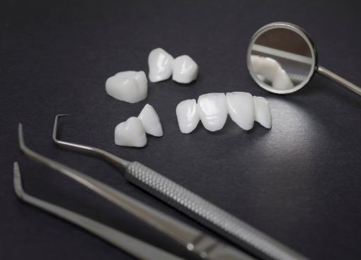 Several dental crowns on table next to dental mirrors