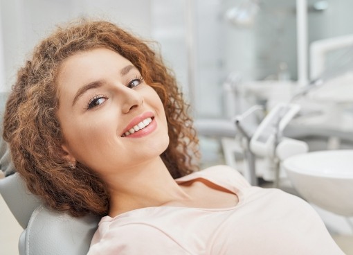 Smiling woman with curly hair leaning back in dental chair