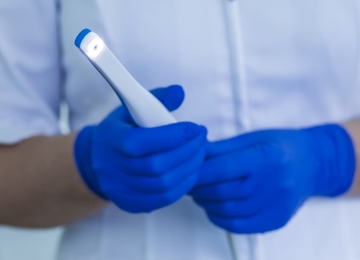 Dental team member holding thin white scanning device