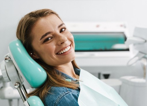 Female dental patient sitting in chair and smiling