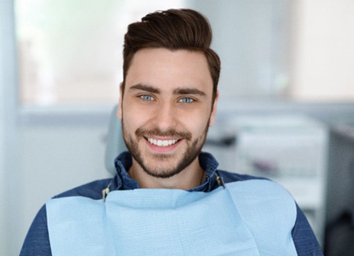 Man with beard sitting in dental chair and smiling