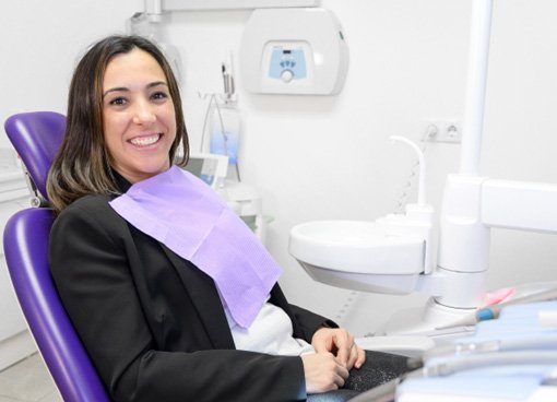 Female patient sitting in dental chair and smiling