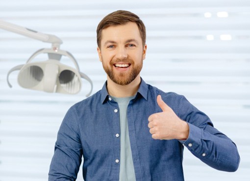 Male dental patient smiling and giving a thumbs up