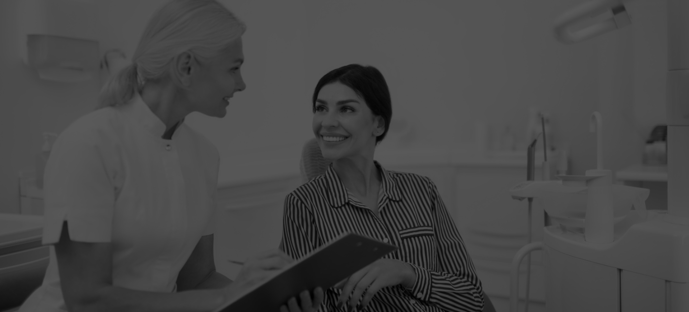 Dental team member holding tablet and asking a patient questions