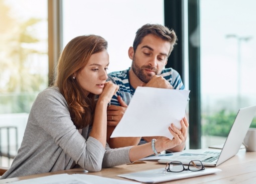 Man and woman sitting at table looking at paper together