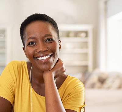 Woman in yellow shirt smiling in living room