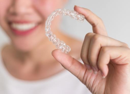 Smiling person holding Invisalign tray