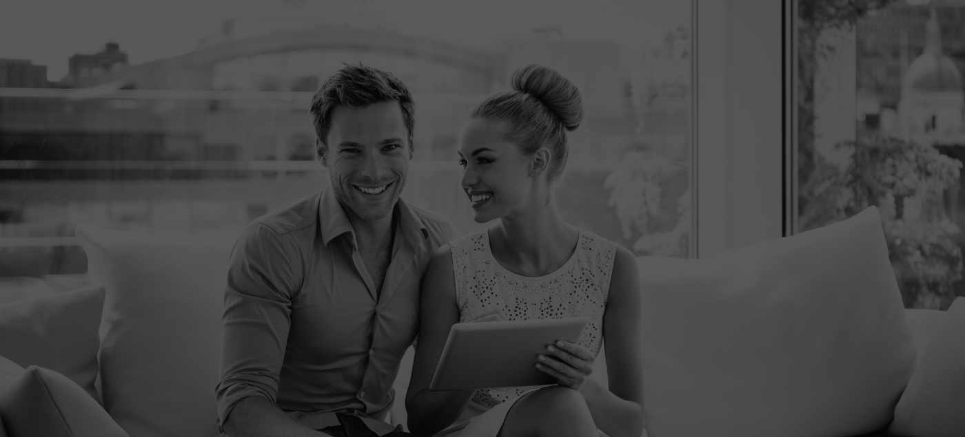 Smiling man and woman sitting on couch with tablet