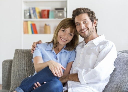 Smiling man and woman holding each other on couch