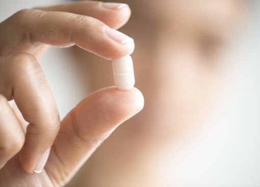 Close up of person holding white pill